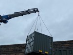 a small shipping container being delivered on a hiab