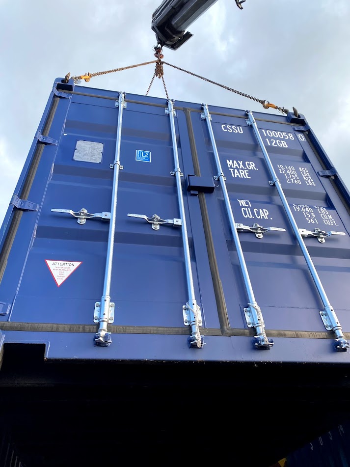 a blue 20 foot shipping container on a craine
