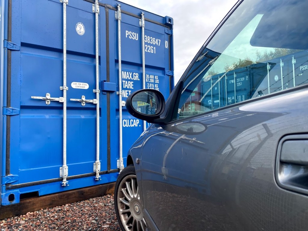 a car parked infront of a shipping container