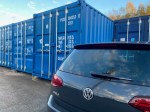 a car parked next to four shipping containers