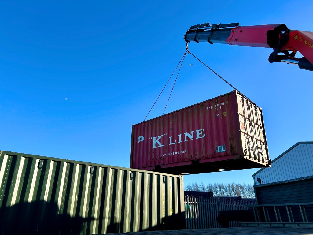 a HIAB delivering a K LINE shipping container into position on a storage depot