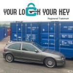 a car parked next to shipping containers on a self storage depot