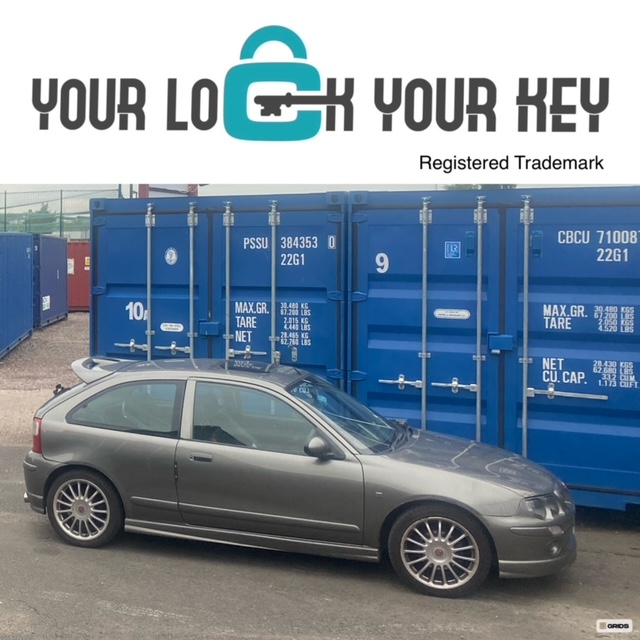 sports car parked next to two shipping containers on a self storage site