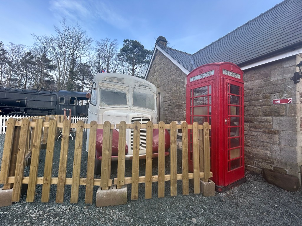 vintage vehicle next to a telephone kiosk outside a cafe premises