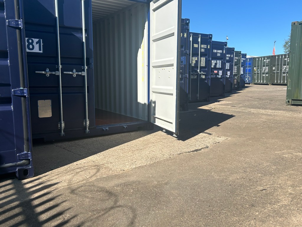 several shipping containers on a storage facility with one shipping container showing an open door