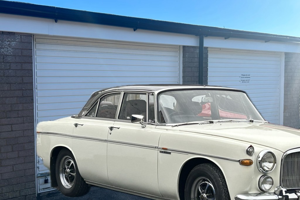 A vintage Rover motorcar parked next to a lock up garage for rent