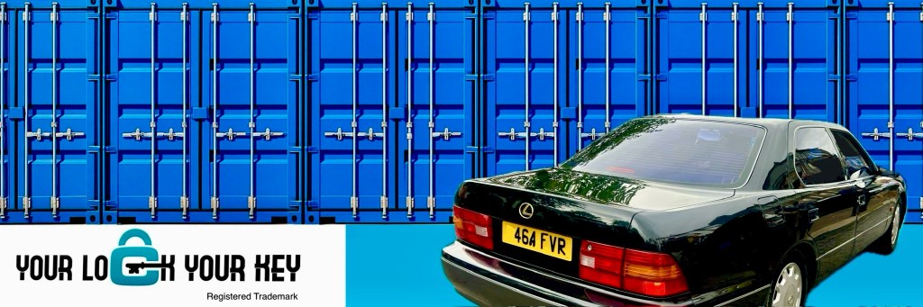 a motor car beside a row of blue shipping containers.