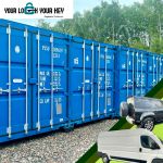 vehicles beside a row of shipping containers