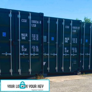 a row of green shipping containers used for self storage purposes.