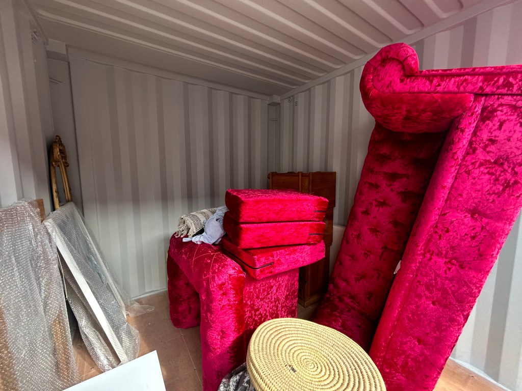 Interior of a storage container filled with plush red furniture and packing materials.