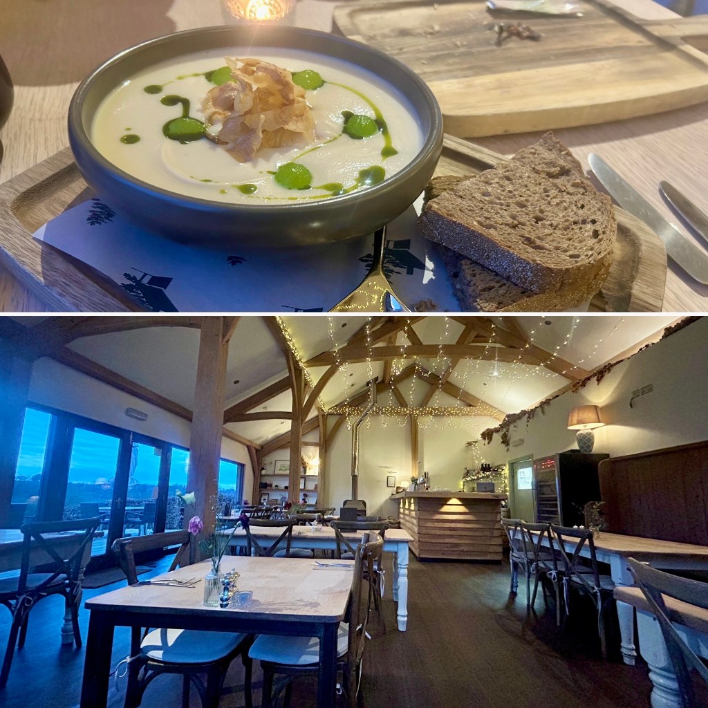 A bowl of Cumbrian creamy soup garnished with crispy toppings and drizzled with green oil, accompanied by a slice of brown bread.