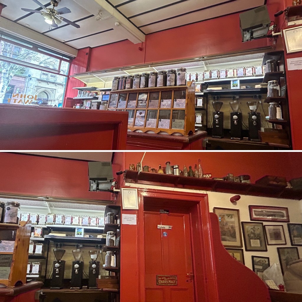Interior view of a cozy cafe with red walls, featuring a wooden display of jars and a coffee grinder setup.