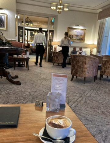 Inn On the Lake, Glenridding, Cumbria showing the inside of the building sat at a table with a cup of coffee.